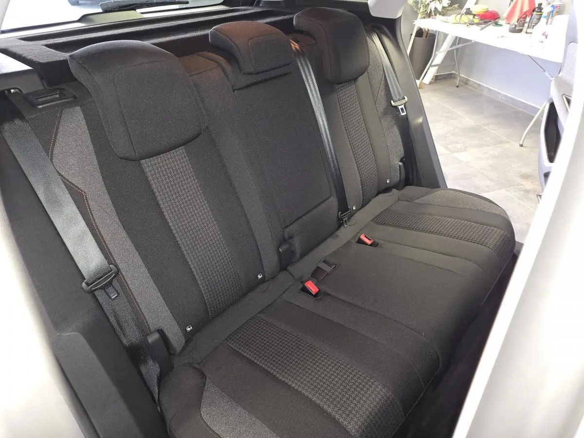 Vue intérieure de la banquette arrière noire en tissu du Peugeot 3008 gris, avec ceintures de sécurité visibles.