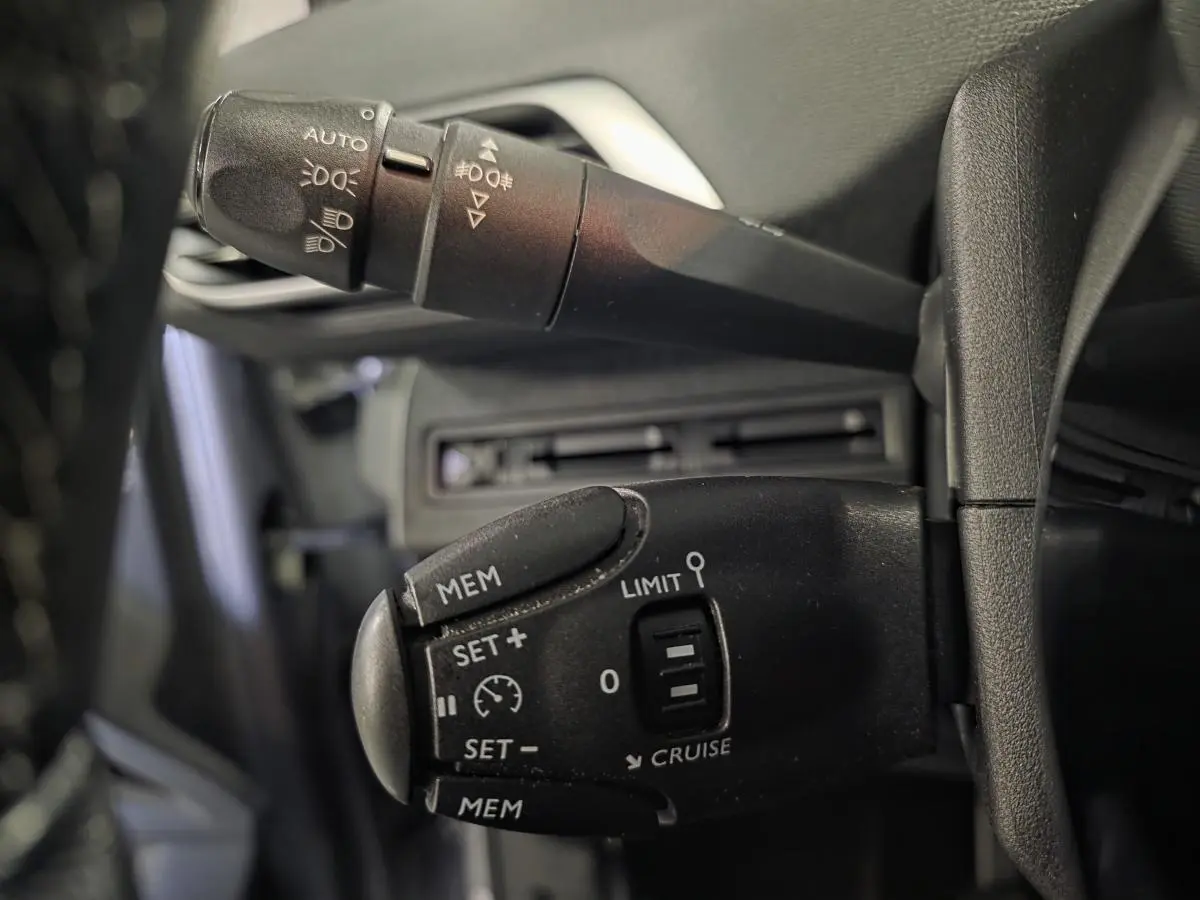 Gros plan sur les commandes de régulateur et feux du Peugeot 3008 gris, côté gauche du volant.