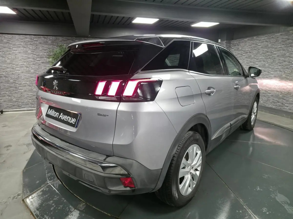 Vue 3/4 arrière droite d’un Peugeot 3008 gris métallisé avec feux arrière à LED et toit noir contrasté.