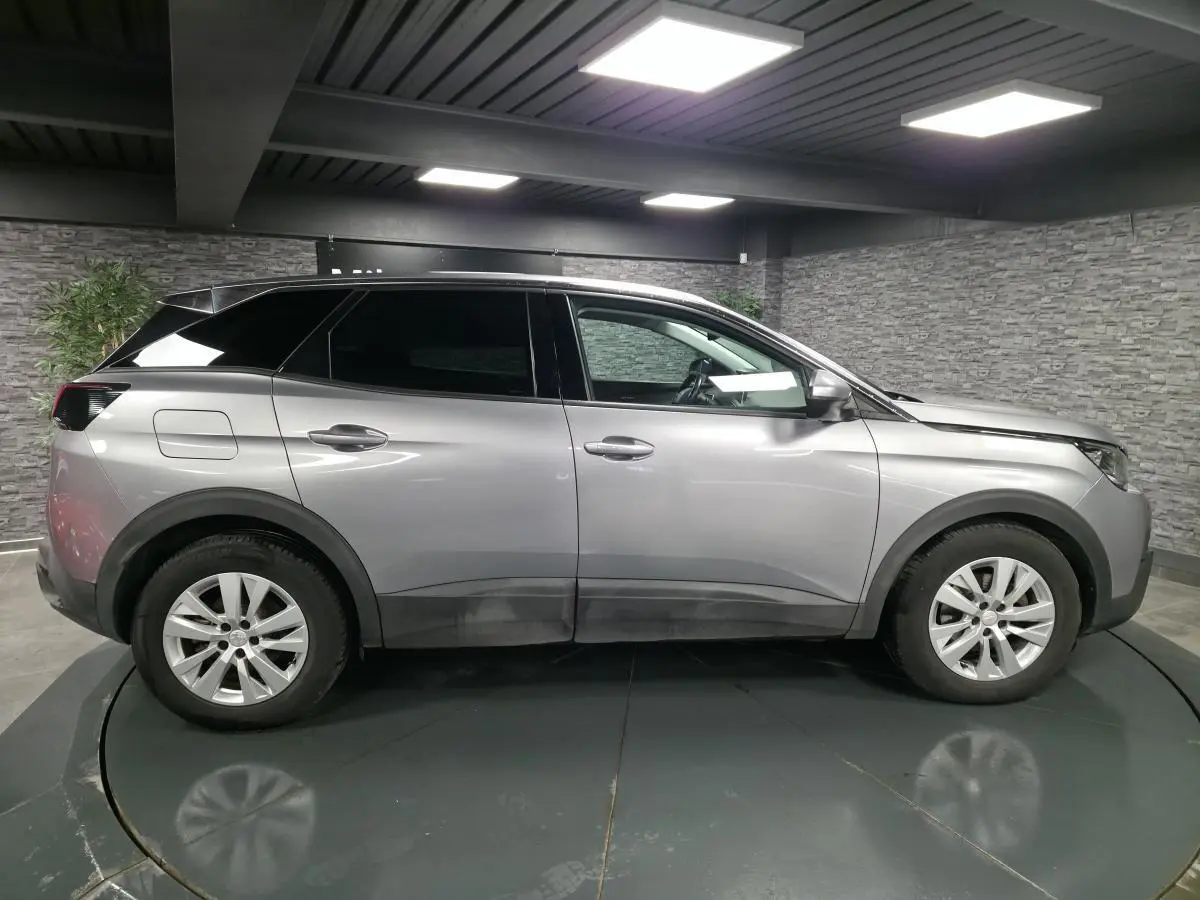 Vue profil droit d’un Peugeot 3008 gris métallisé 2018 avec jantes alliage 17 pouces dans un garage.