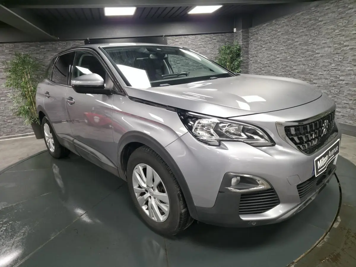 Peugeot 3008 gris métallisé vue 3/4 avant droit en intérieur avec calandre chromée et jantes alliage 17 pouces.