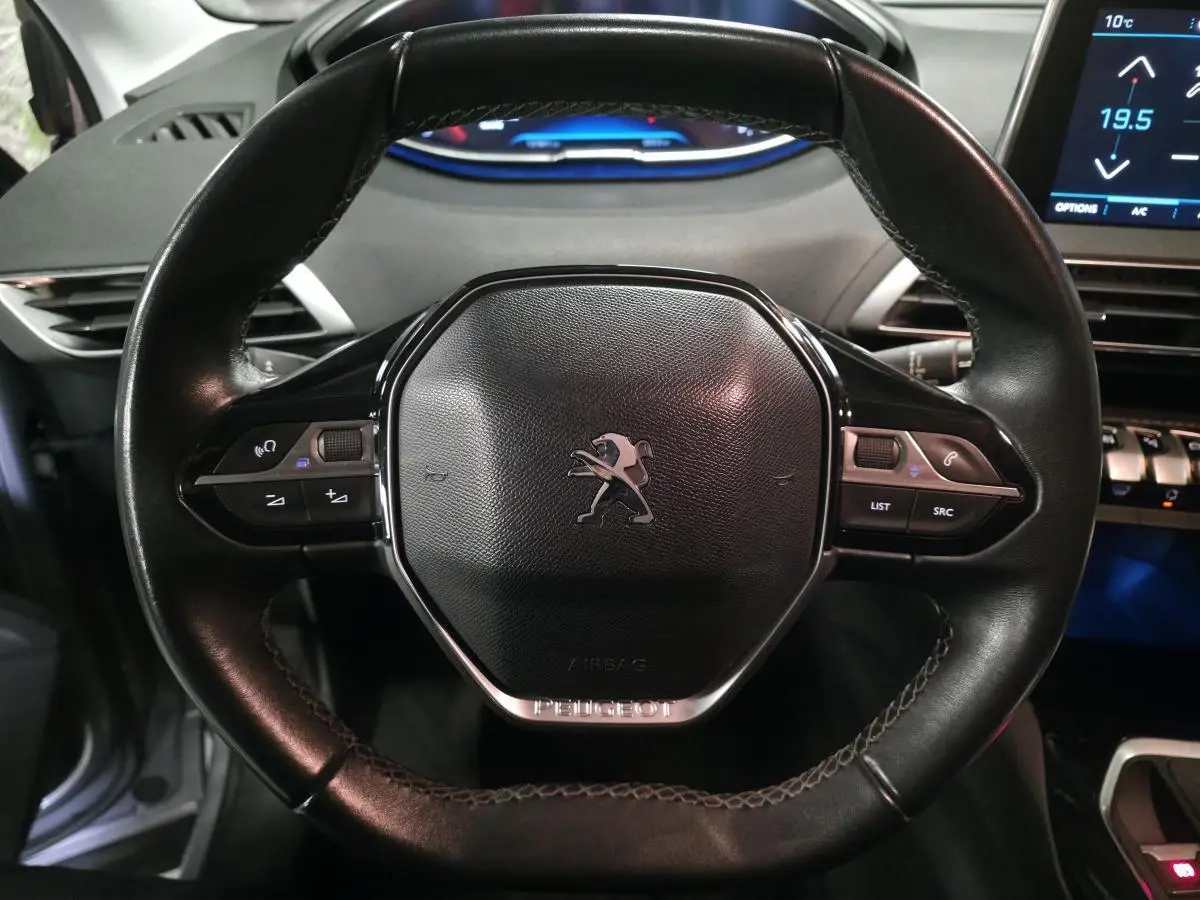 Volant cuir noir compact de Peugeot 3008 2018 avec commandes multifonctions et logo lion central.