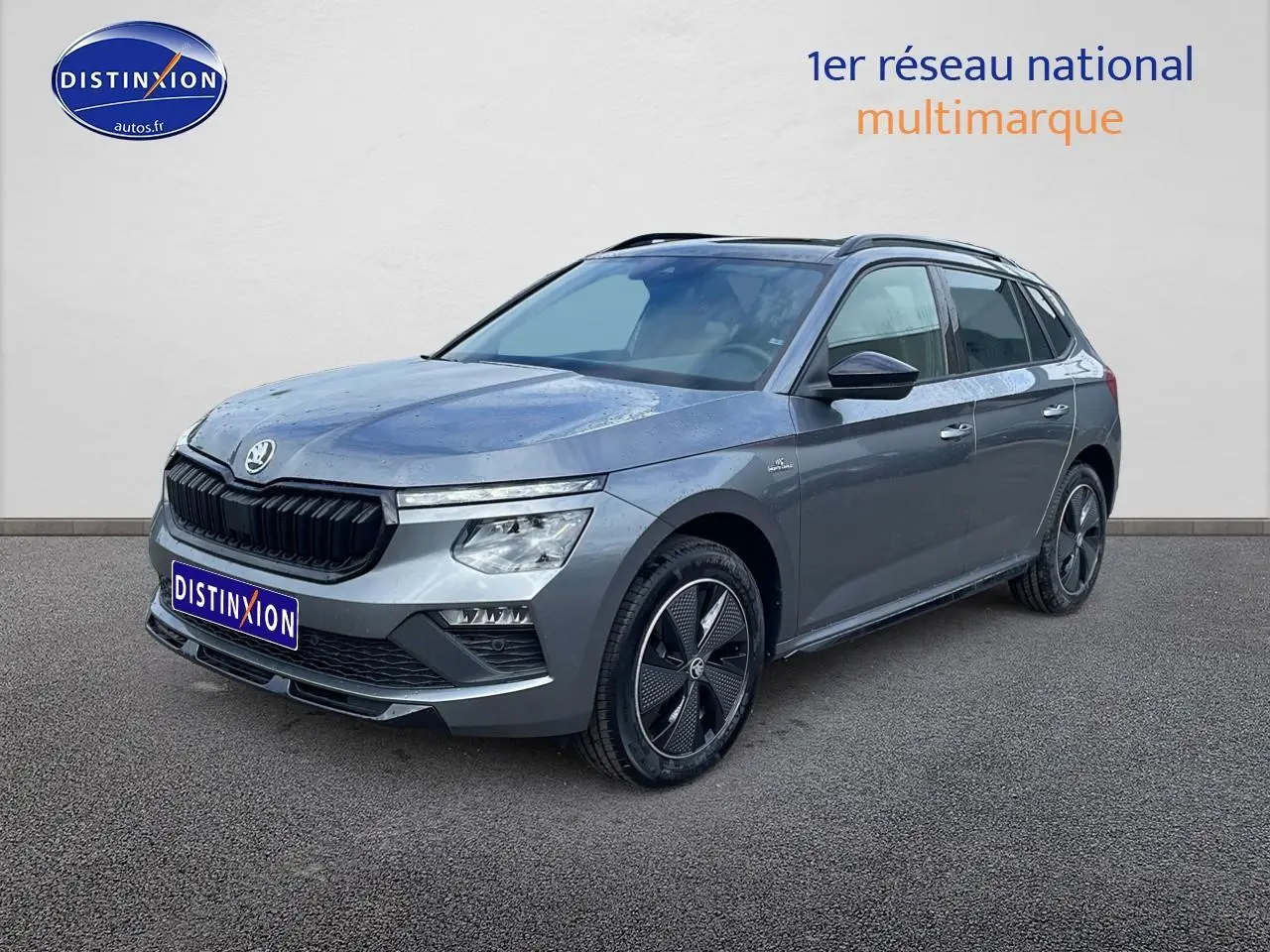 Vue 3/4 avant droite d'un Skoda Kamiq gris graphite avec jantes alu noires et toit panoramique en verre.