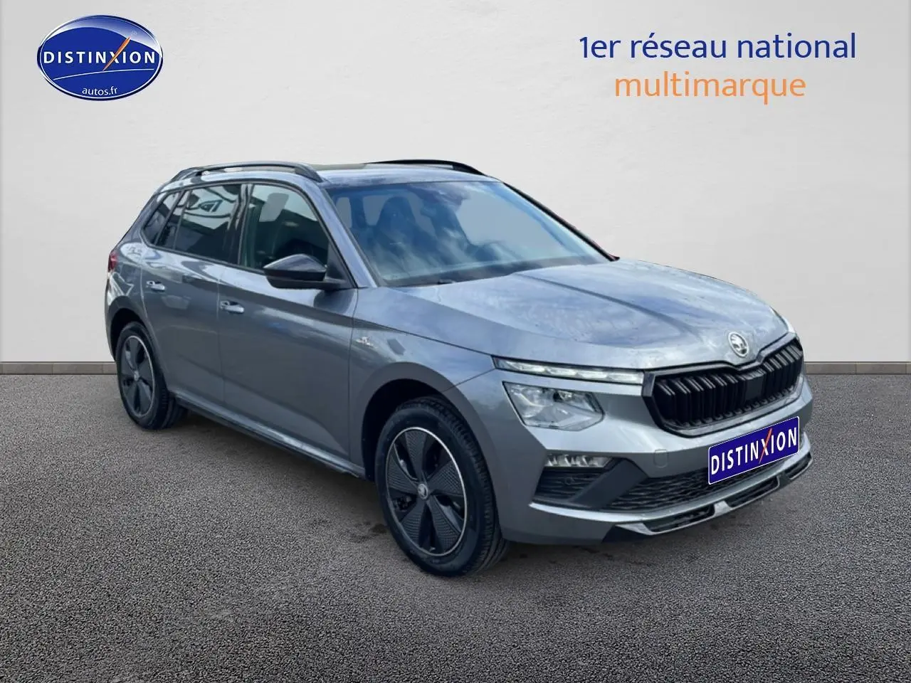 Vue 3/4 avant droite d’un Skoda Kamiq gris graphite avec jantes alu et barres de toit noires.