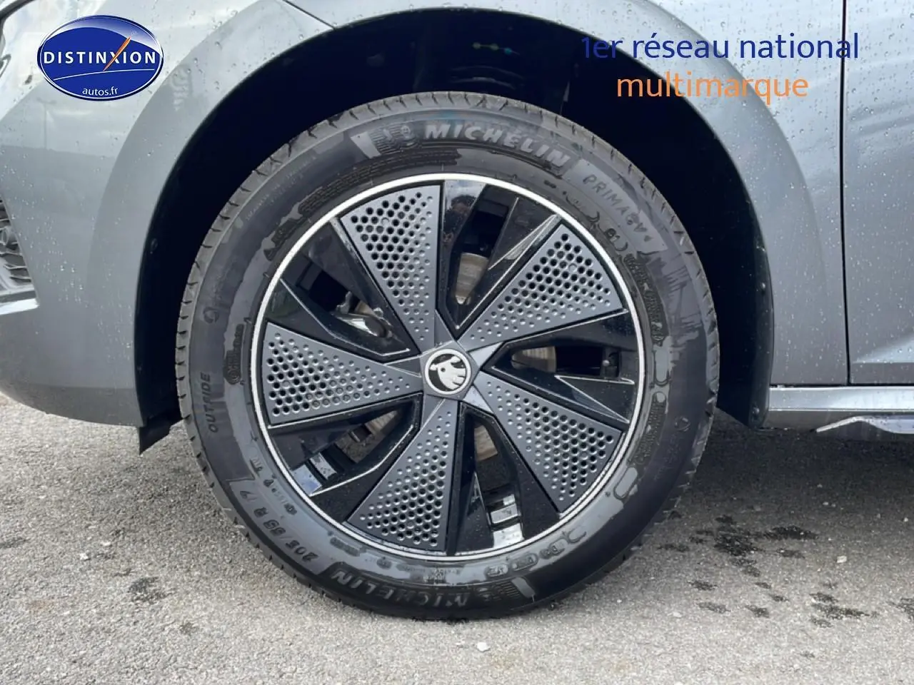Gros plan sur la roue avant droite du Skoda Kamiq gris graphite avec jante alu au design moderne perforé.