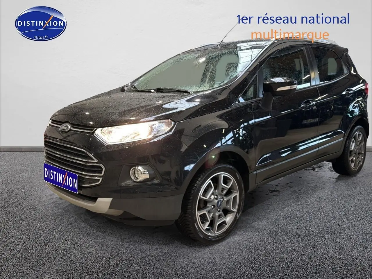 Ford EcoSport noir vue 3/4 avant droit avec jantes alu et phares allumés en intérieur showroom.