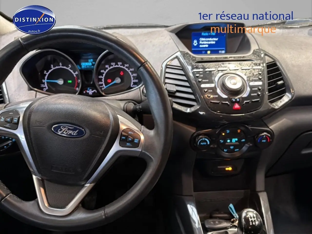 Vue intérieure centrée sur le volant cuir multifonction et la console centrale du Ford EcoSport noir 2017, boîte manuelle.