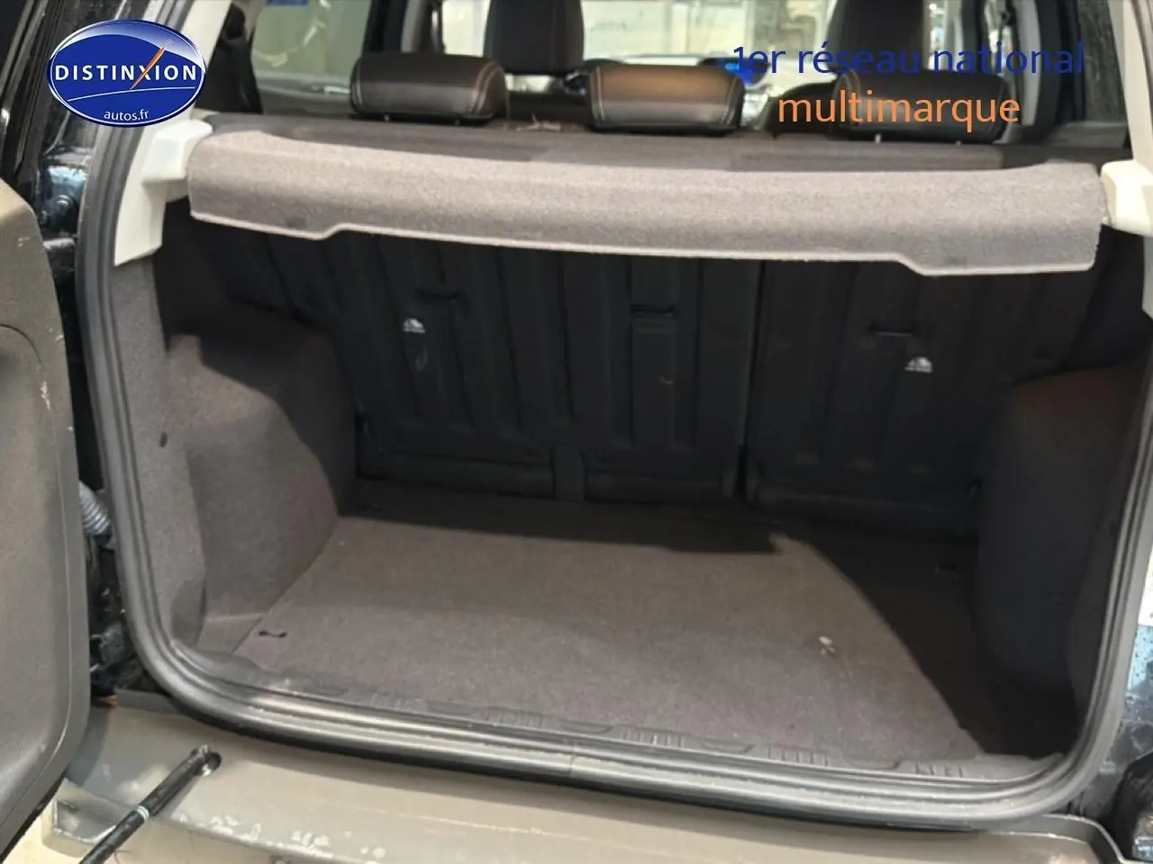 Coffre ouvert d’un Ford EcoSport noir 2017, vue de l’arrière montrant la tablette cache-bagages et la banquette rabattable.