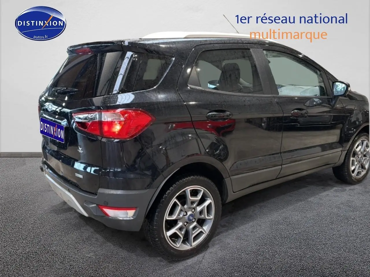 Ford EcoSport noir en 3/4 arrière droit, avec jantes alu et barres de toit visibles sur fond neutre.