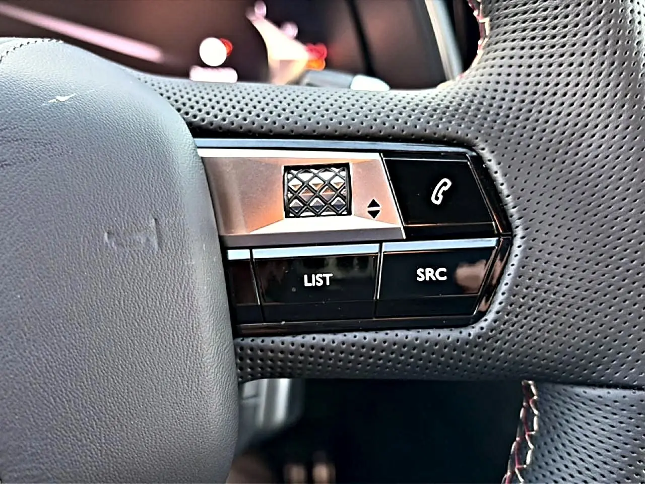 Gros plan sur les commandes gauche du volant en cuir perforé noir du DS7 1.5 BlueHDi 130 Performance Line 2026.