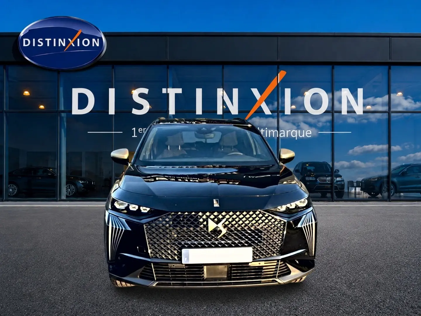 Vue de face d'un DS7 noir 2026 avec calandre diamantée et phares LED distinctifs, devant une vitrine Distinxion.