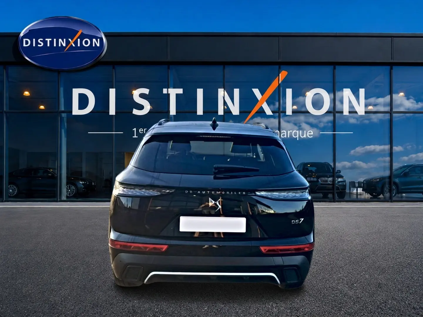 Vue arrière d'un DS7 noir 2026 garé devant une vitrine avec logo Distinxion en arrière-plan.