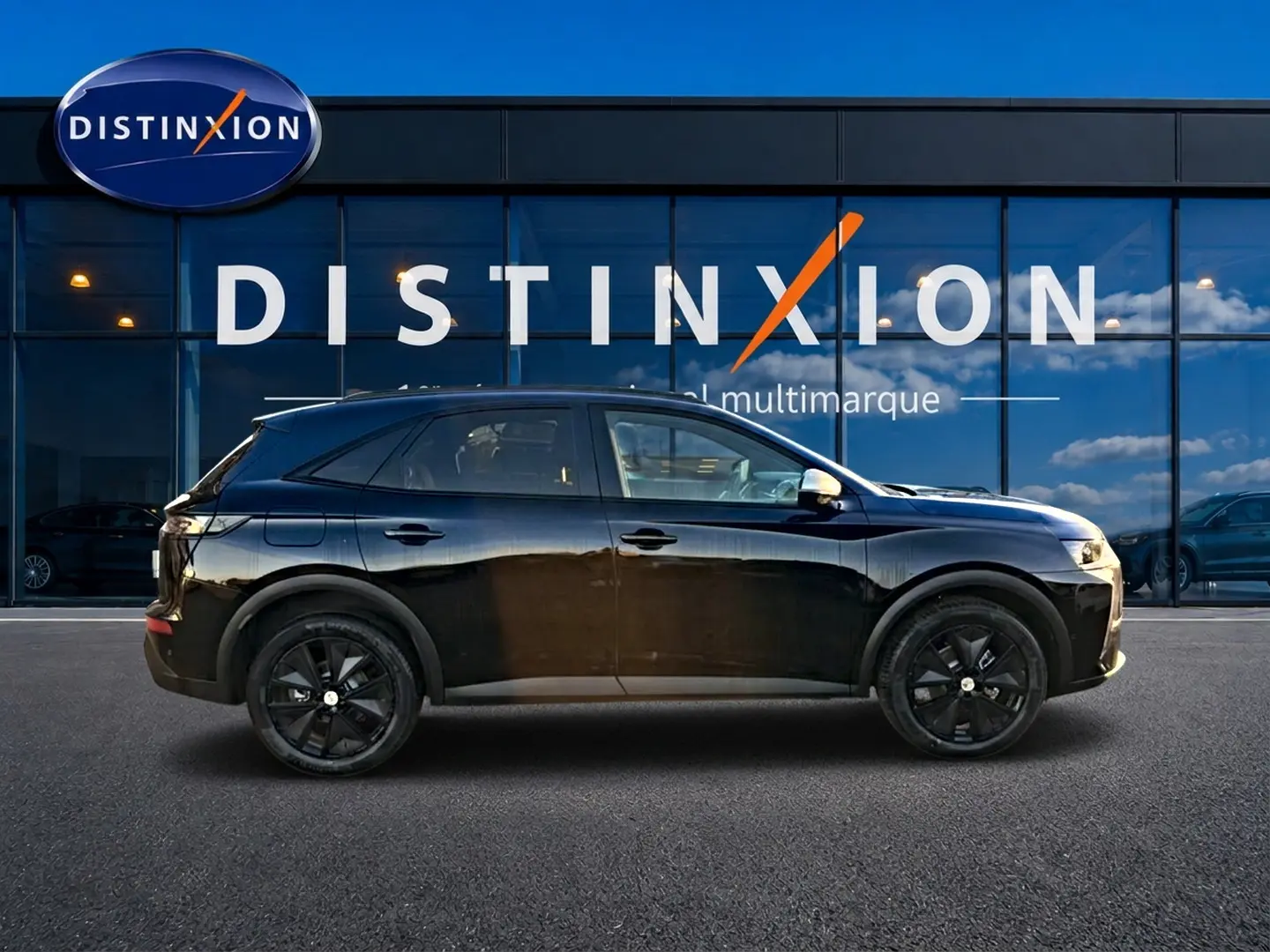 Vue de profil côté gauche d'un DS7 noir 2026 avec jantes noires, garé devant une vitrine Distinxion.