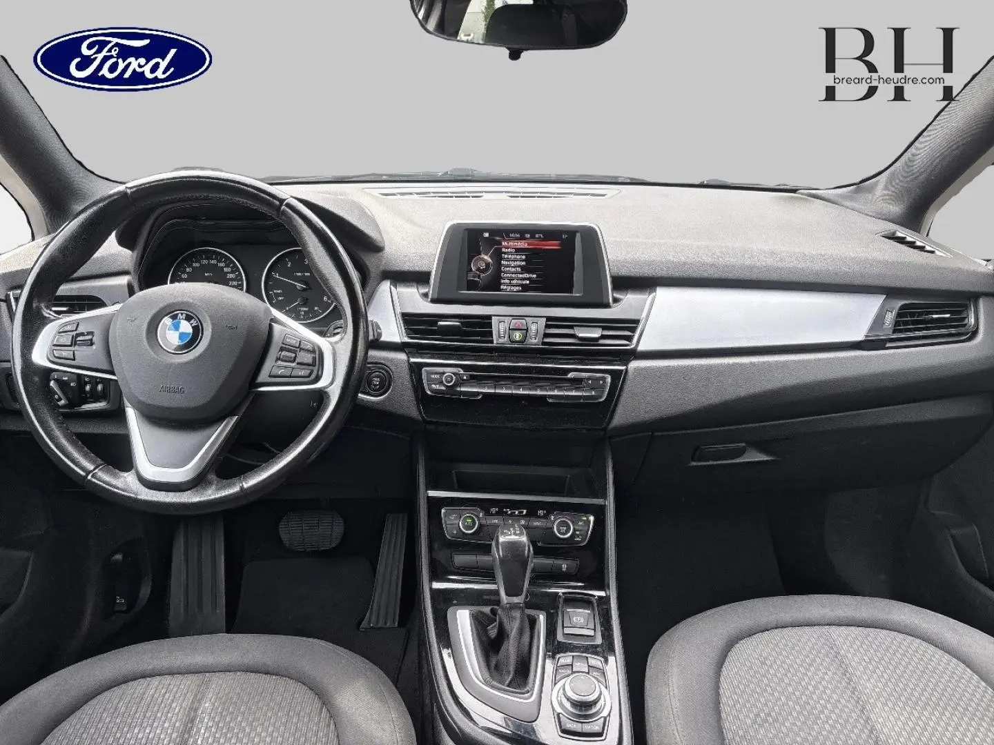 Vue frontale de l'habitacle BMW Série 2 Active Tourer 216dA 2015, avec volant cuir multifonction et console centrale noire.