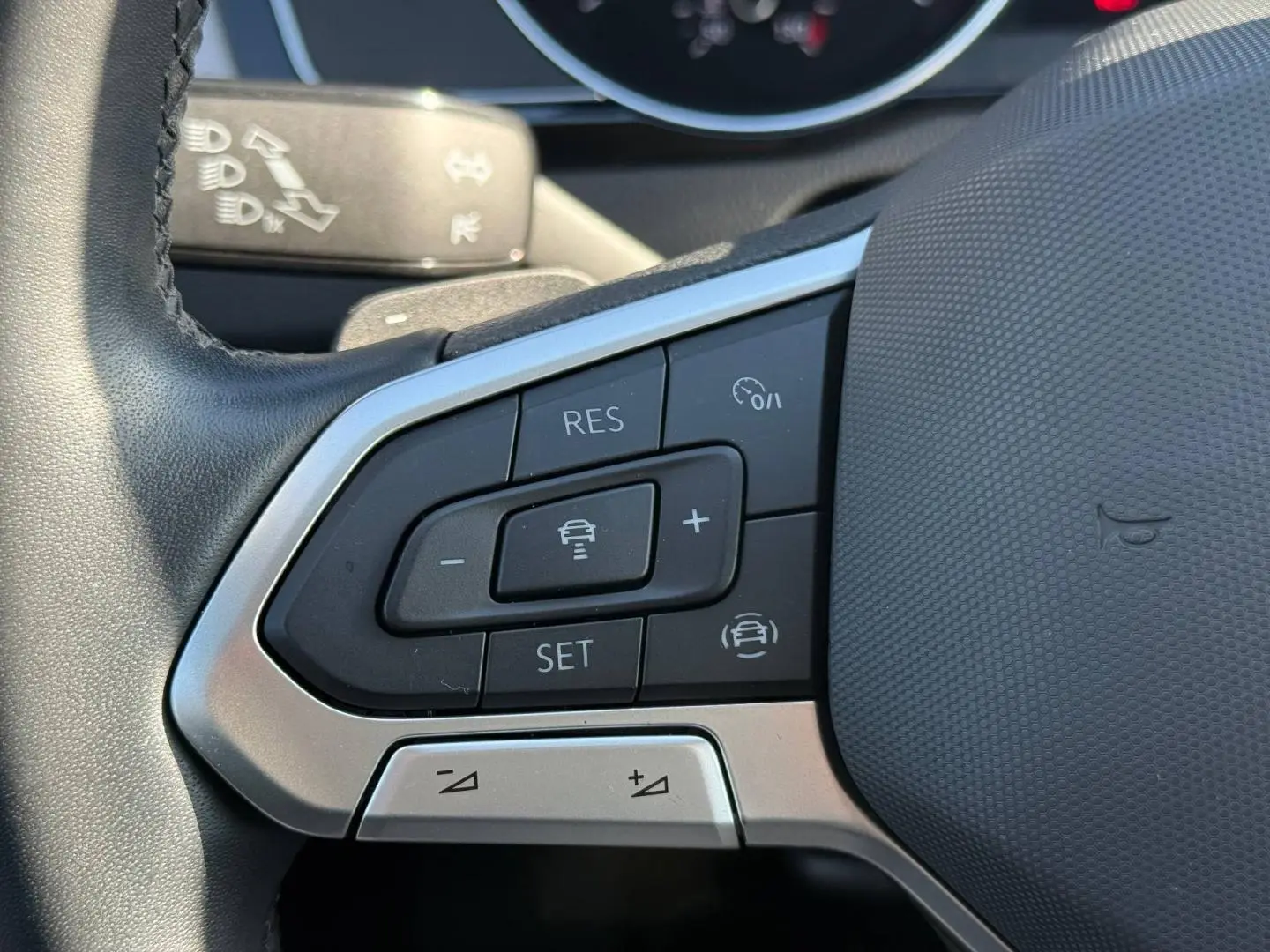 Gros plan sur les commandes de régulateur de vitesse au volant cuir noir d'une Volkswagen Passat SW 2023.