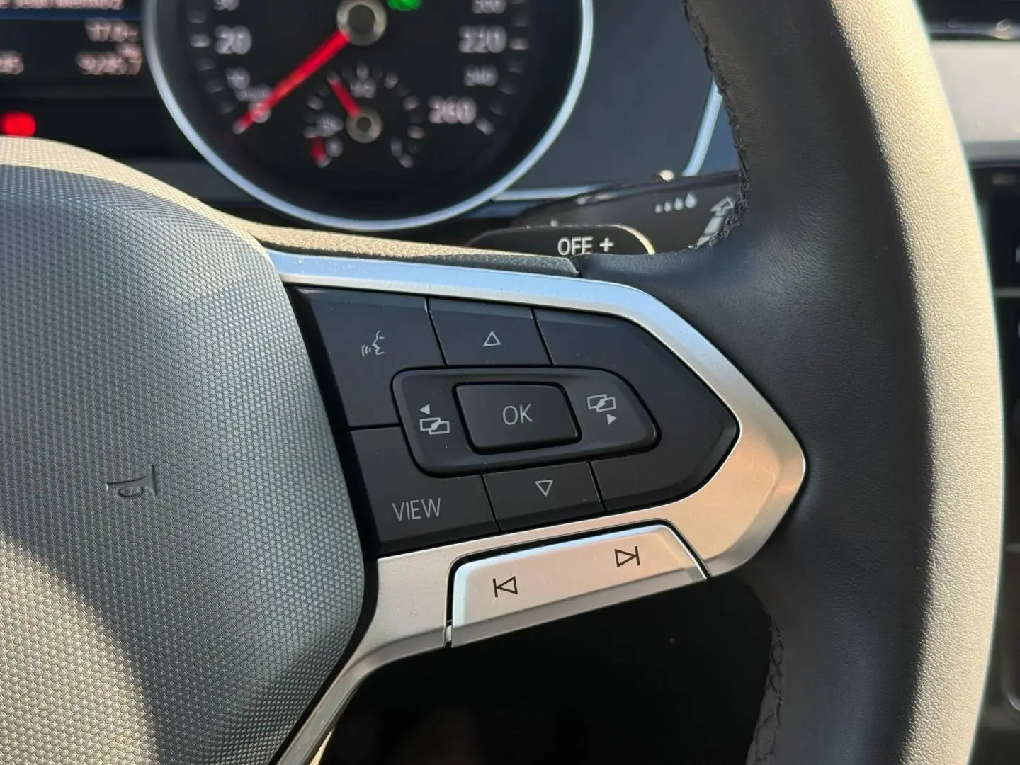 Gros plan sur les commandes multifonctions à droite du volant cuir de la Volkswagen Passat SW noire, avec tableau de bord partiellement visible.