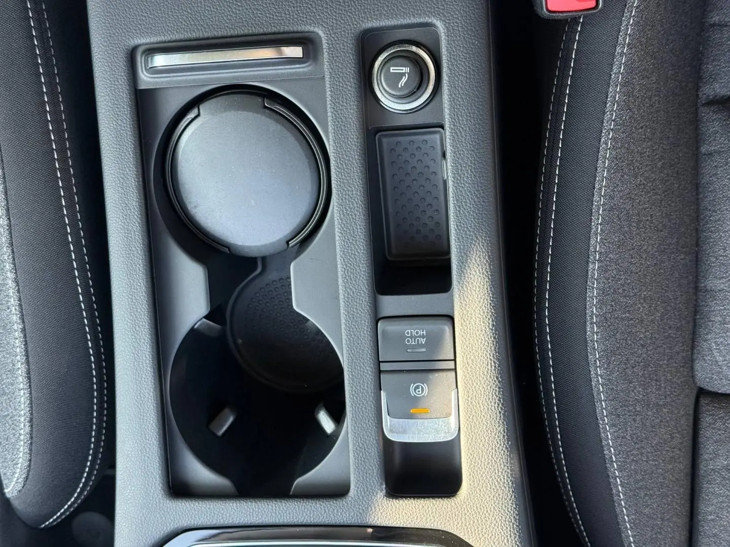 Vue plongeante sur la console centrale noire de la Volkswagen Passat SW 2023, avec porte-gobelets et frein électrique.