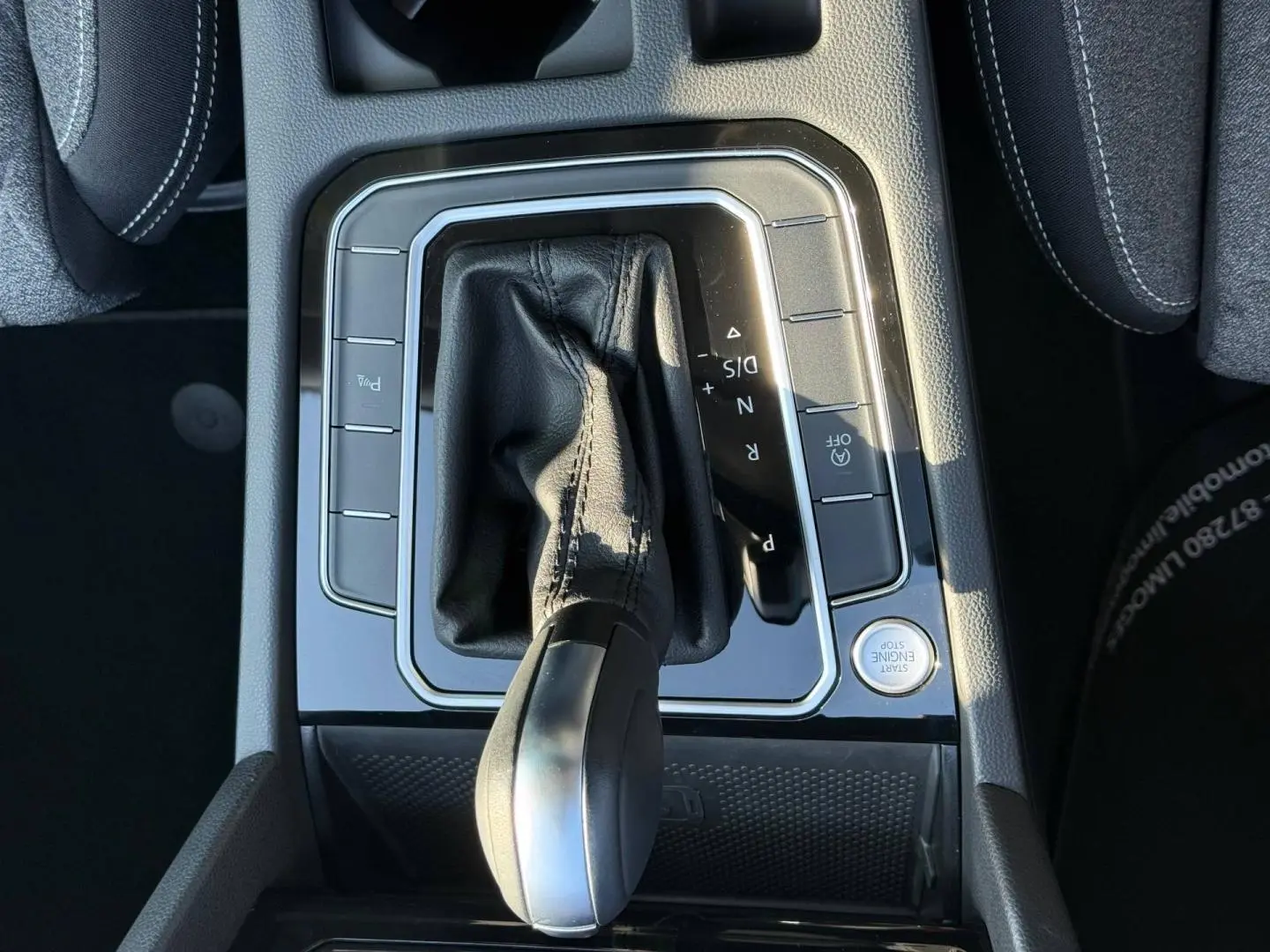 Gros plan sur la console centrale de la Volkswagen Passat SW 2023, levier de vitesse cuir noir et boutons autour.