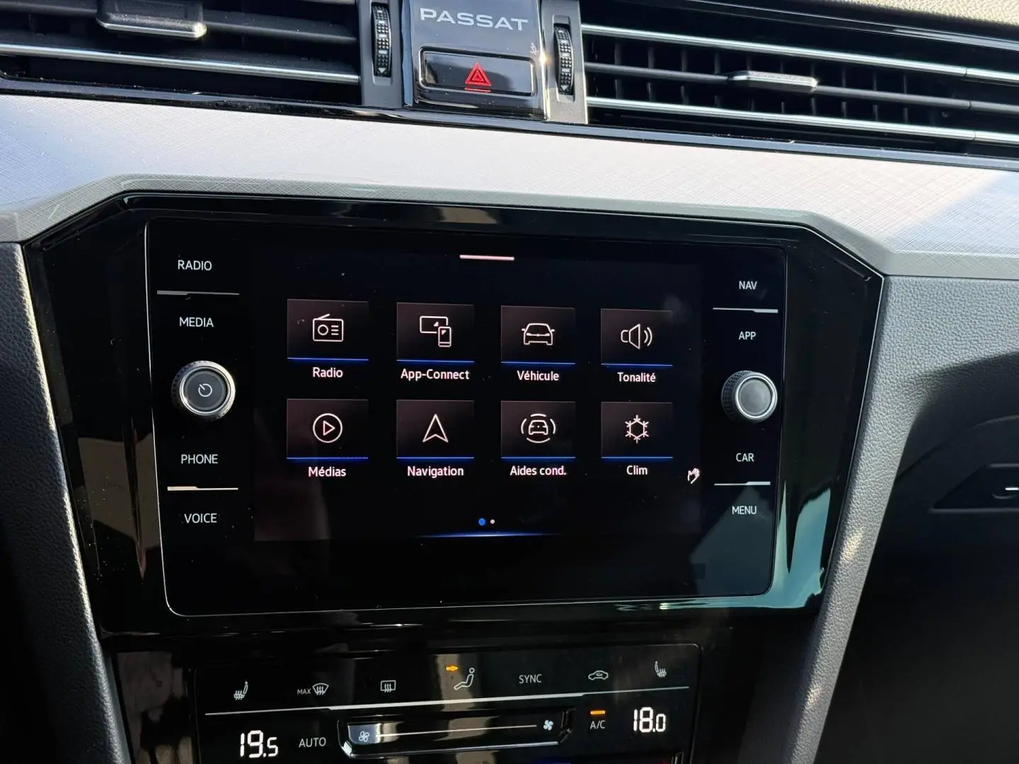 Écran tactile central de la Volkswagen Passat SW 2023, vue rapprochée du tableau de bord noir avec commandes digitales.