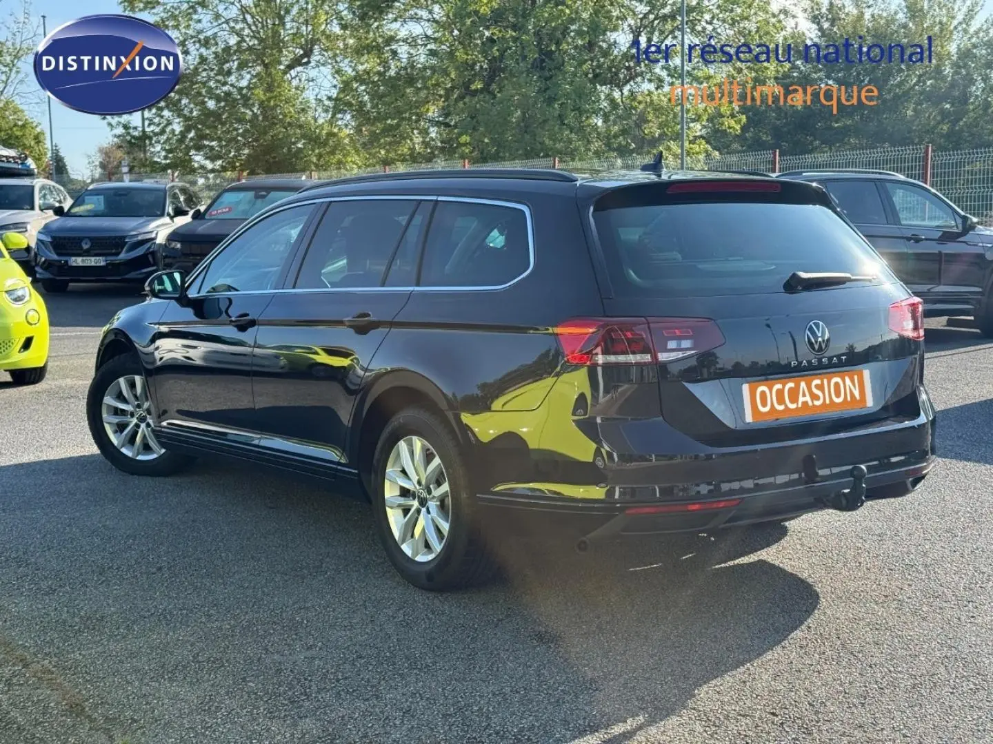 Volkswagen Passat SW noir intense nacré vue 3/4 arrière droit avec barres de toit et attelage visible.