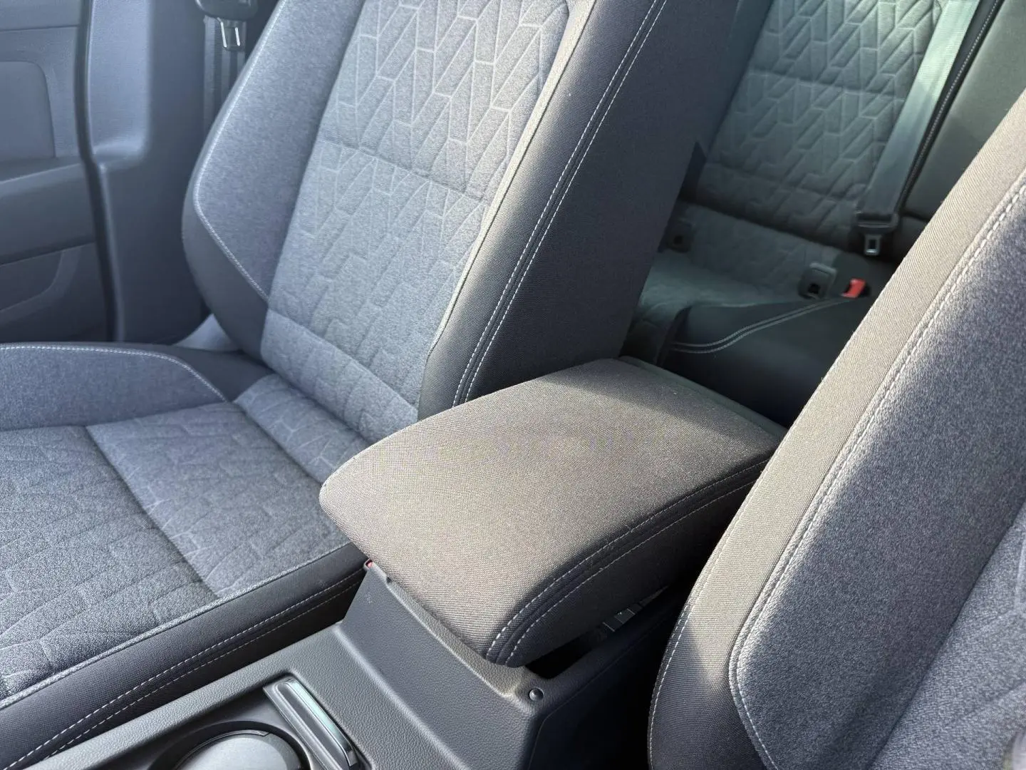 Accoudoir central avant et sièges tissu gris avec surpiqûres blanches dans l'habitacle de la Volkswagen Passat SW 2023.