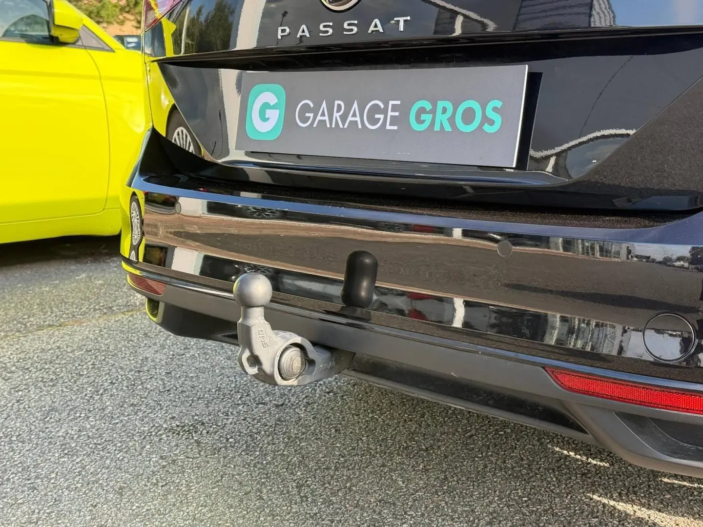 Vue rapprochée arrière d’une Volkswagen Passat SW noire intense nacrée avec attelage visible et plaque Garage Gros.