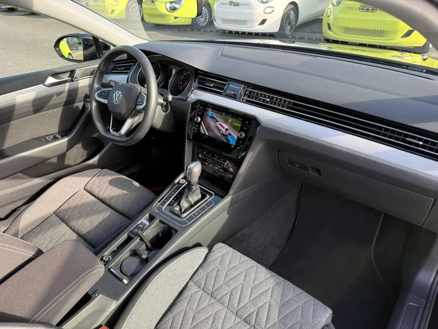 Vue intérieure côté conducteur de la Volkswagen Passat SW 2.0 TDI Business avec tableau de bord moderne et sièges tissu noir.