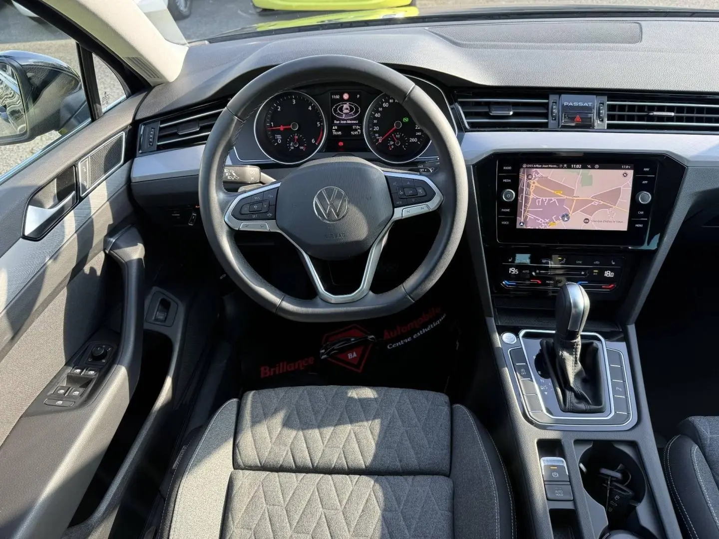 Vue intérieure de la Volkswagen Passat SW 2023, tableau de bord noir avec volant cuir multifonction et écran tactile GPS.