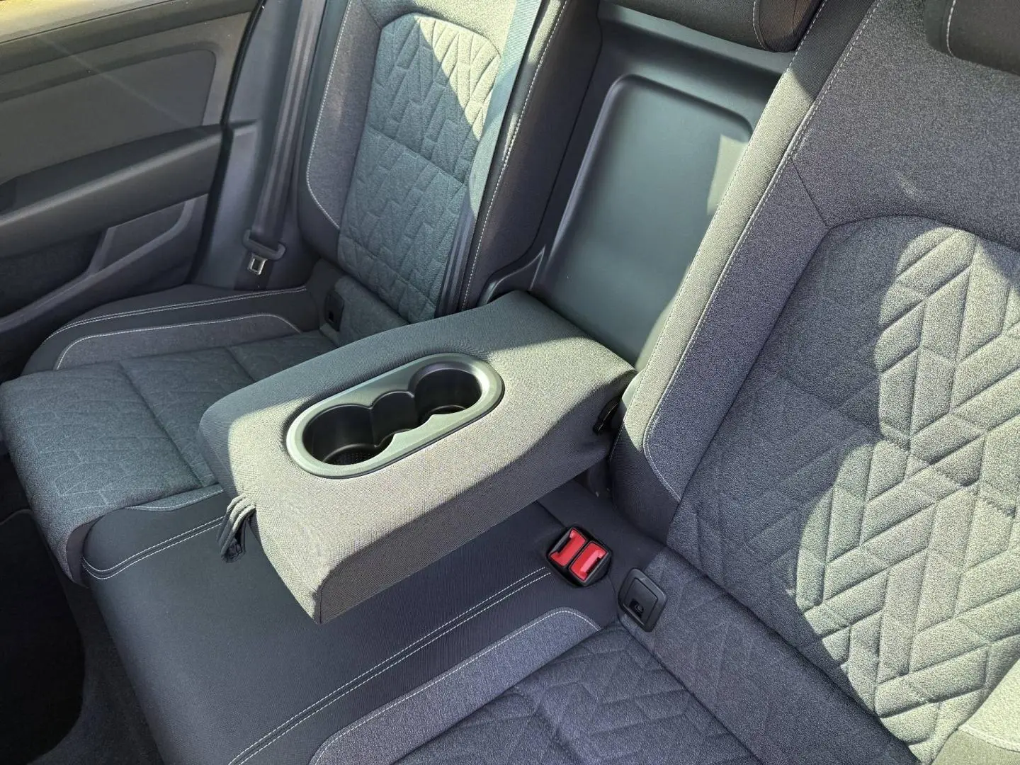Vue rapprochée de la banquette arrière grise de la Volkswagen Passat SW 2023 avec accoudoir central et porte-gobelets intégrés.