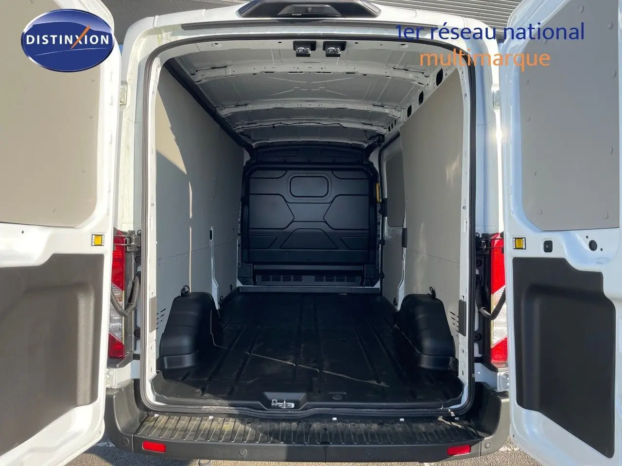 Vue arrière ouverte du fourgon Ford Transit blanc 2023 montrant l'espace de chargement vide et les portes battantes ouvertes.