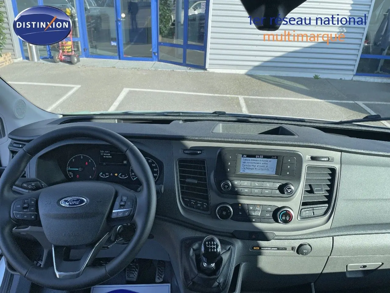 Vue intérieure du tableau de bord et volant du Ford Transit Fourgon blanc 2023 avec boîte manuelle, affichage central et commandes au volant.
