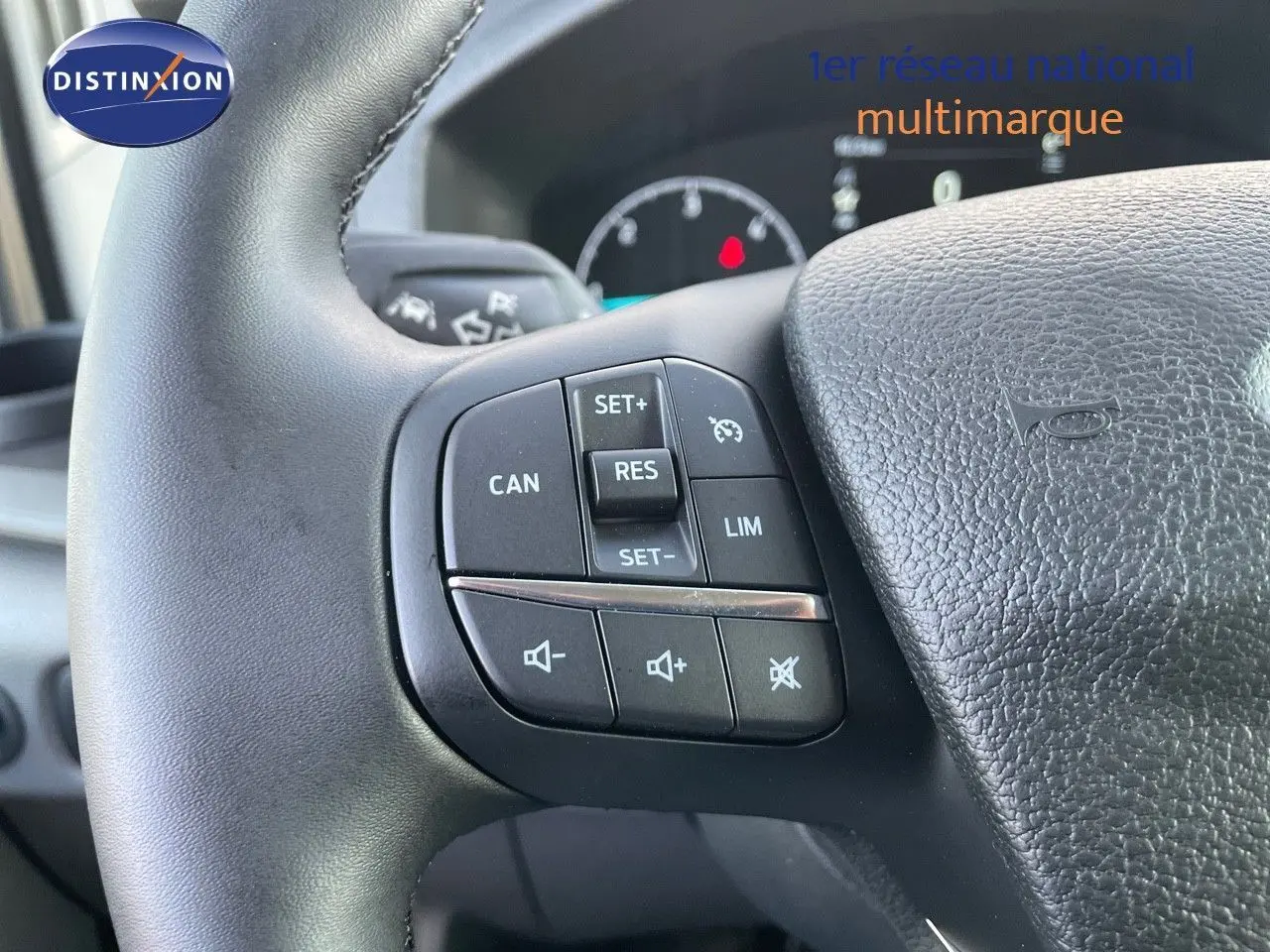 Gros plan sur les commandes au volant noir du Ford Transit Fourgon blanc, mettant en valeur les boutons de régulateur de vitesse.