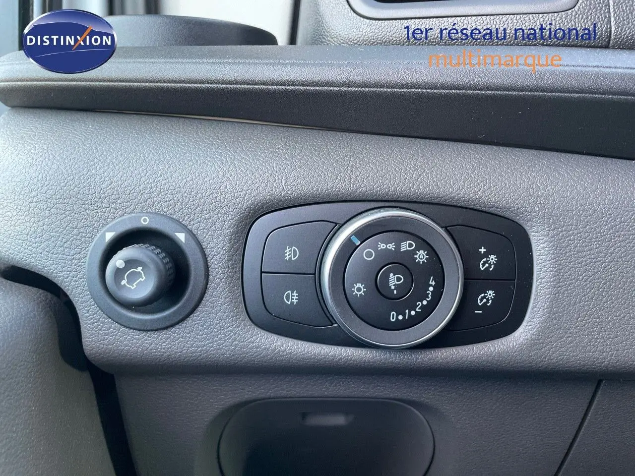 Gros plan sur le panneau de commande des phares et réglages lumineux du Ford Transit Fourgon blanc 2023.