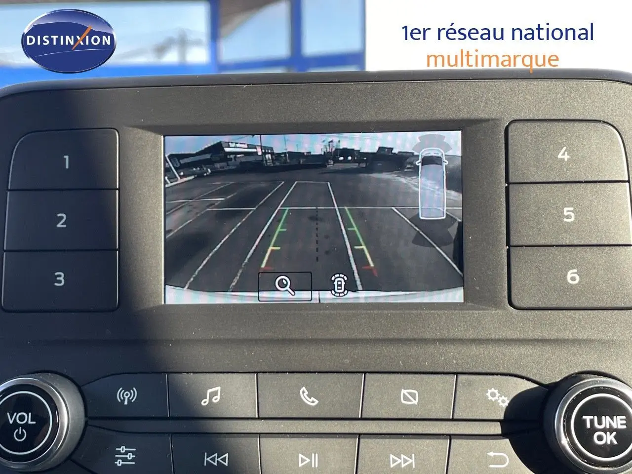 Écran central du Ford Transit blanc 2023 montrant la caméra de recul avec lignes de guidage en parking vide.