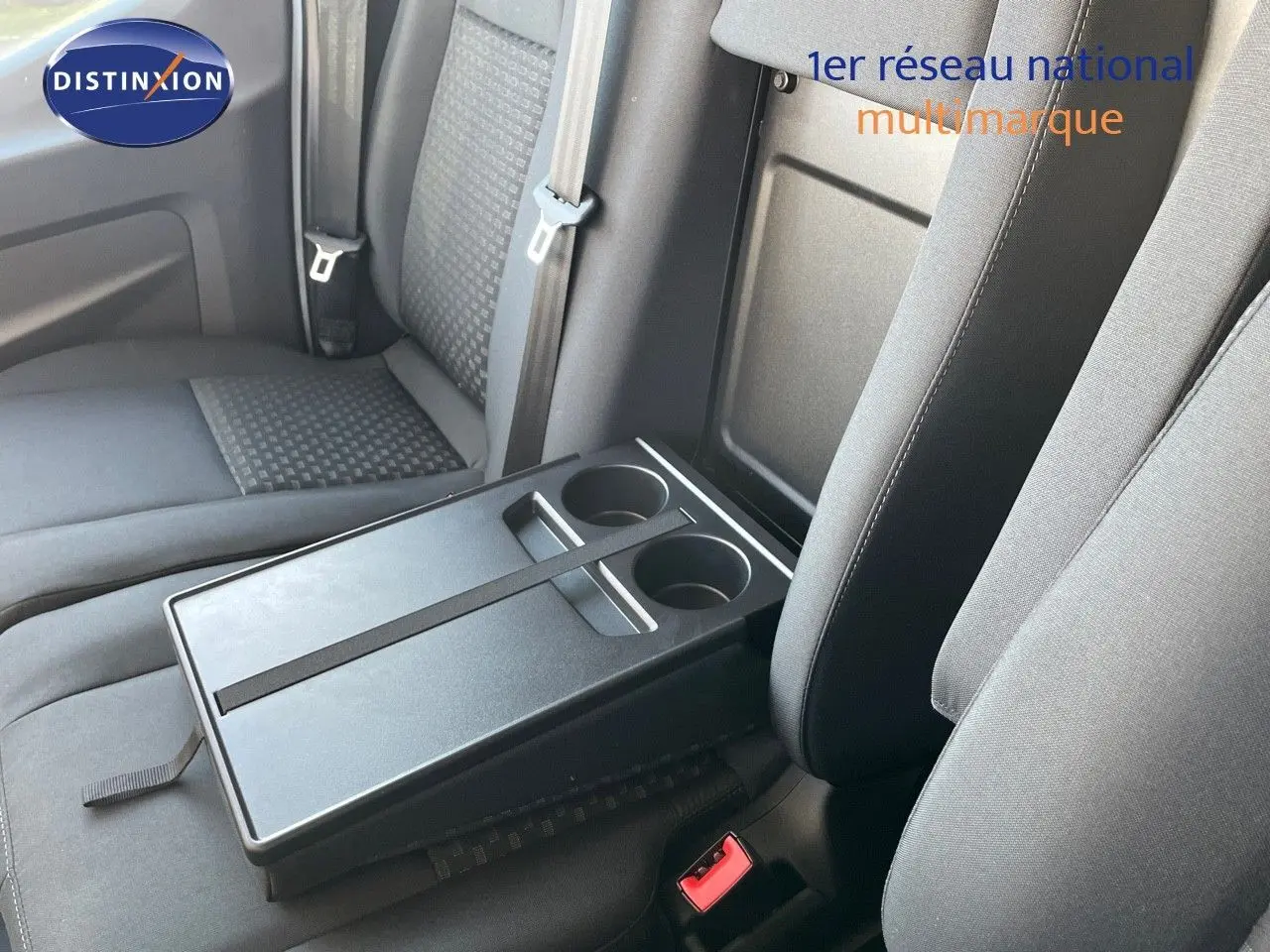 Vue rapprochée de la banquette avant noire du Ford Transit Fourgon blanc avec tablette et porte-gobelets intégrés.