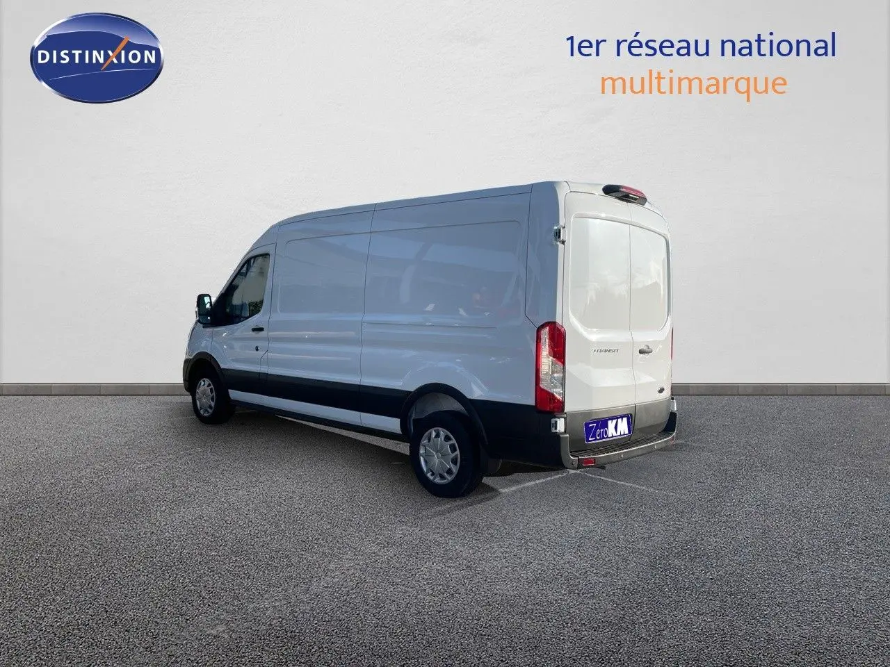 Fourgon Ford Transit blanc vu en 3/4 arrière droit, soulignant sa grande longueur et ses portes arrière fermées.