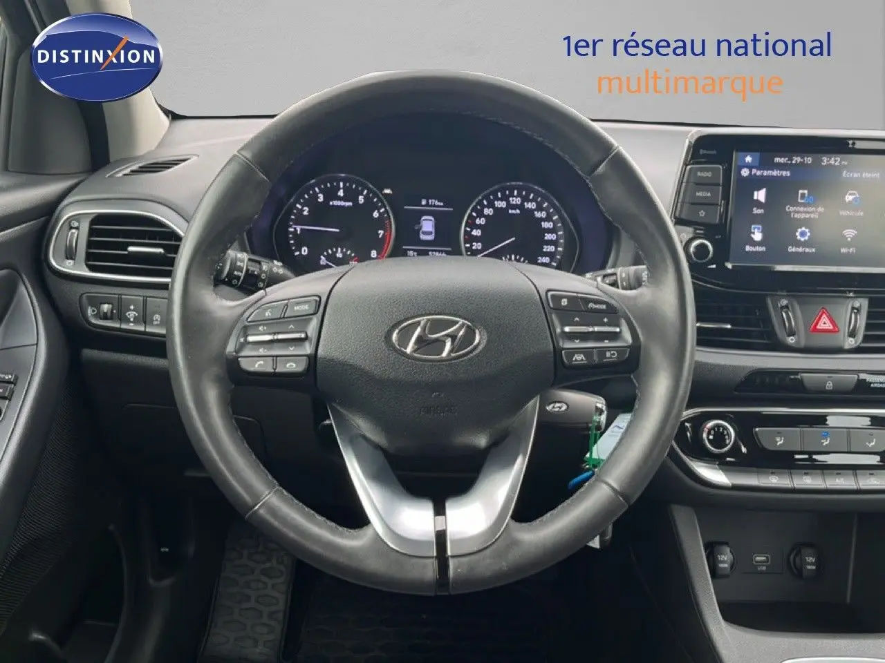 Vue intérieure centrée sur le volant noir de la Hyundai i30 2023 avec tableau de bord et écran tactile visible.