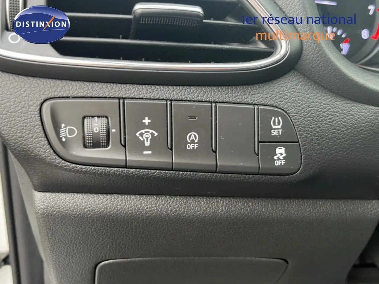 Gros plan sur les commandes de réglage d’éclairage et d’assistance du tableau de bord d’une Hyundai i30 blanche nacrée 2023.