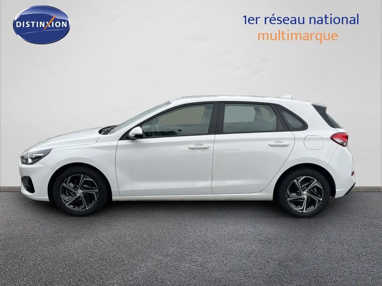 Vue de profil côté gauche d'une Hyundai i30 blanche nacrée 5 portes, avec jantes alliage et lignes épurées.