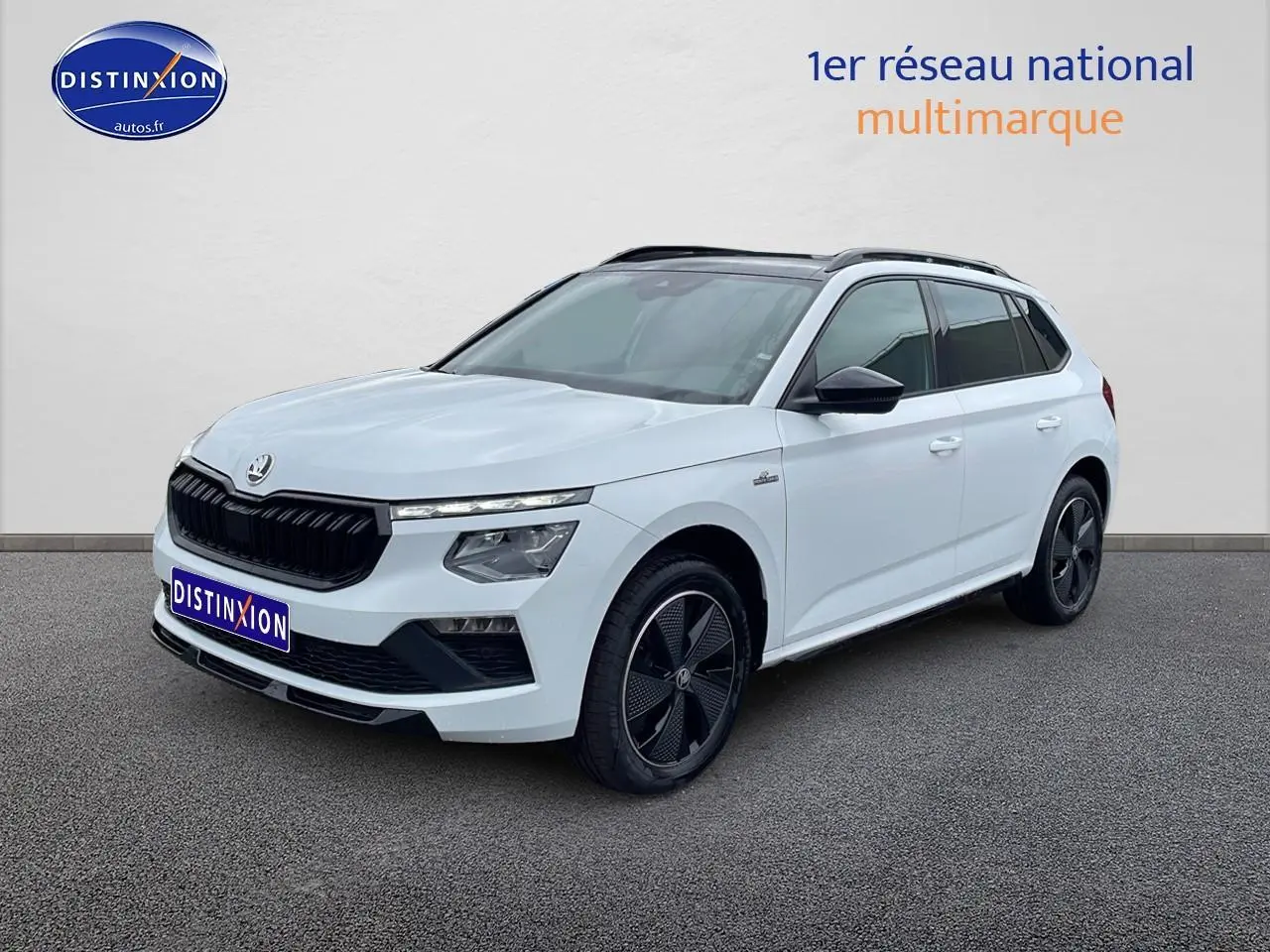 Vue 3/4 avant droite d'un Skoda Kamiq blanc nacré avec toit panoramique et jantes noires distinctives.