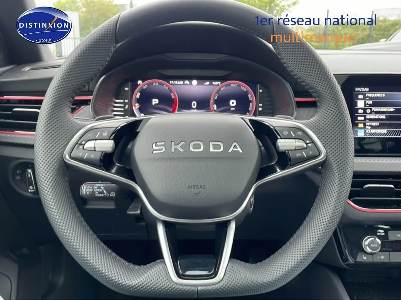 Vue frontale du volant perforé SKODA avec affichage numérique et tableau de bord noir aux touches rouges.