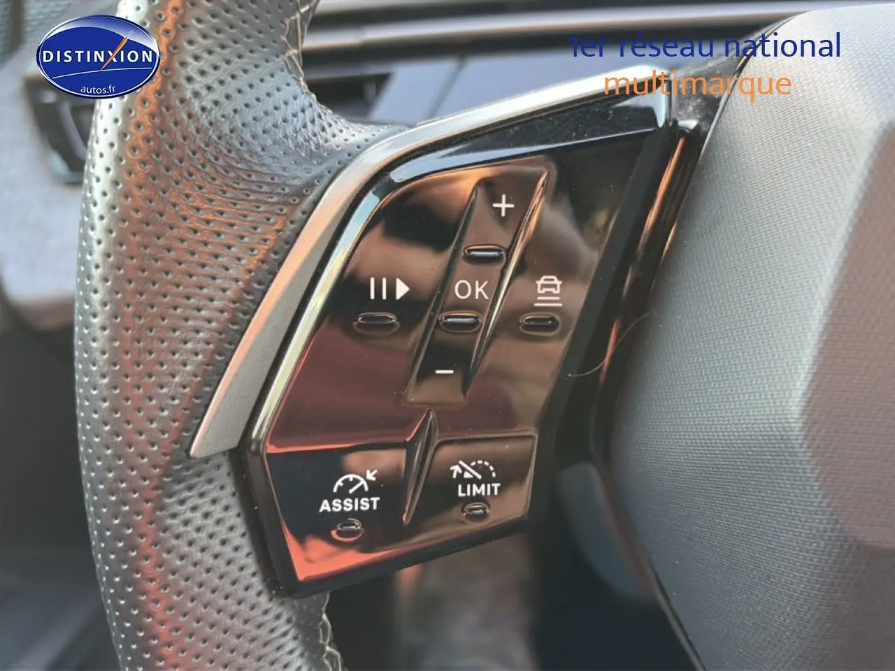 Gros plan sur les commandes multifonctions noires du volant cuir perforé du Peugeot 3008 gris 2025.