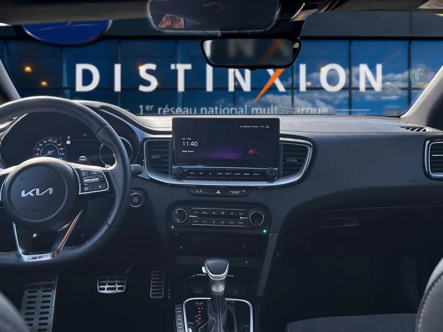 Vue intérieure avant du Kia Xceed gris 2024, tableau de bord avec écran tactile et volant multifonction cuir.
