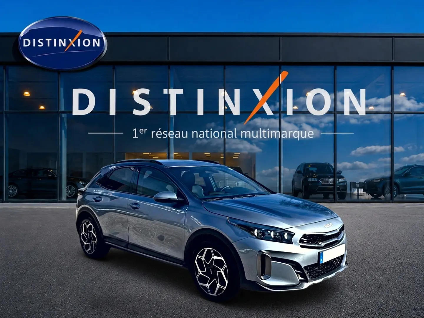 KIA Xceed gris 3/4 avant droit, jantes alu distinctives, devant vitrine du réseau Distinxion.