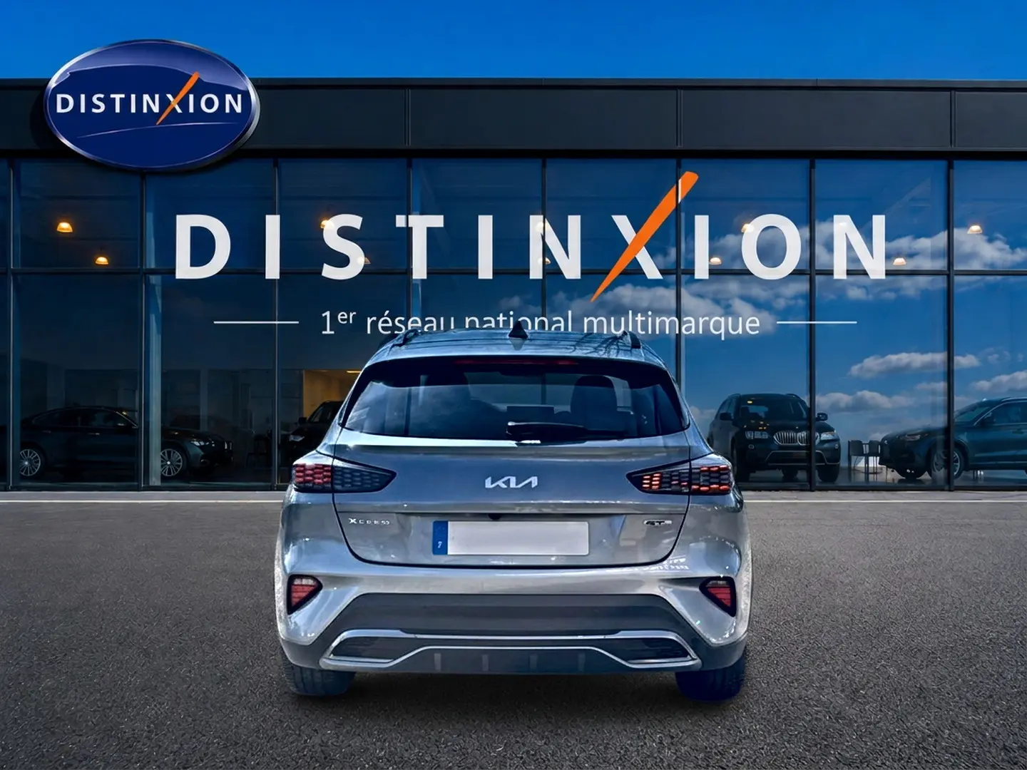 Vue arrière d’un KIA Xceed gris 2024 GT-Line Premium avec feux LED et becquet, devant une vitrine Distinxion.