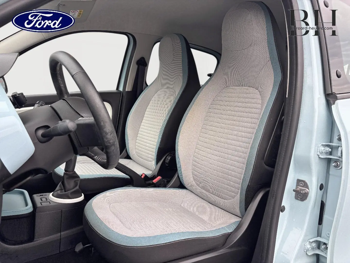 Vue intérieure côté conducteur de la Renault Twingo Bleu Dragée 2014, sièges tissu gris avec surpiqûres bleues.