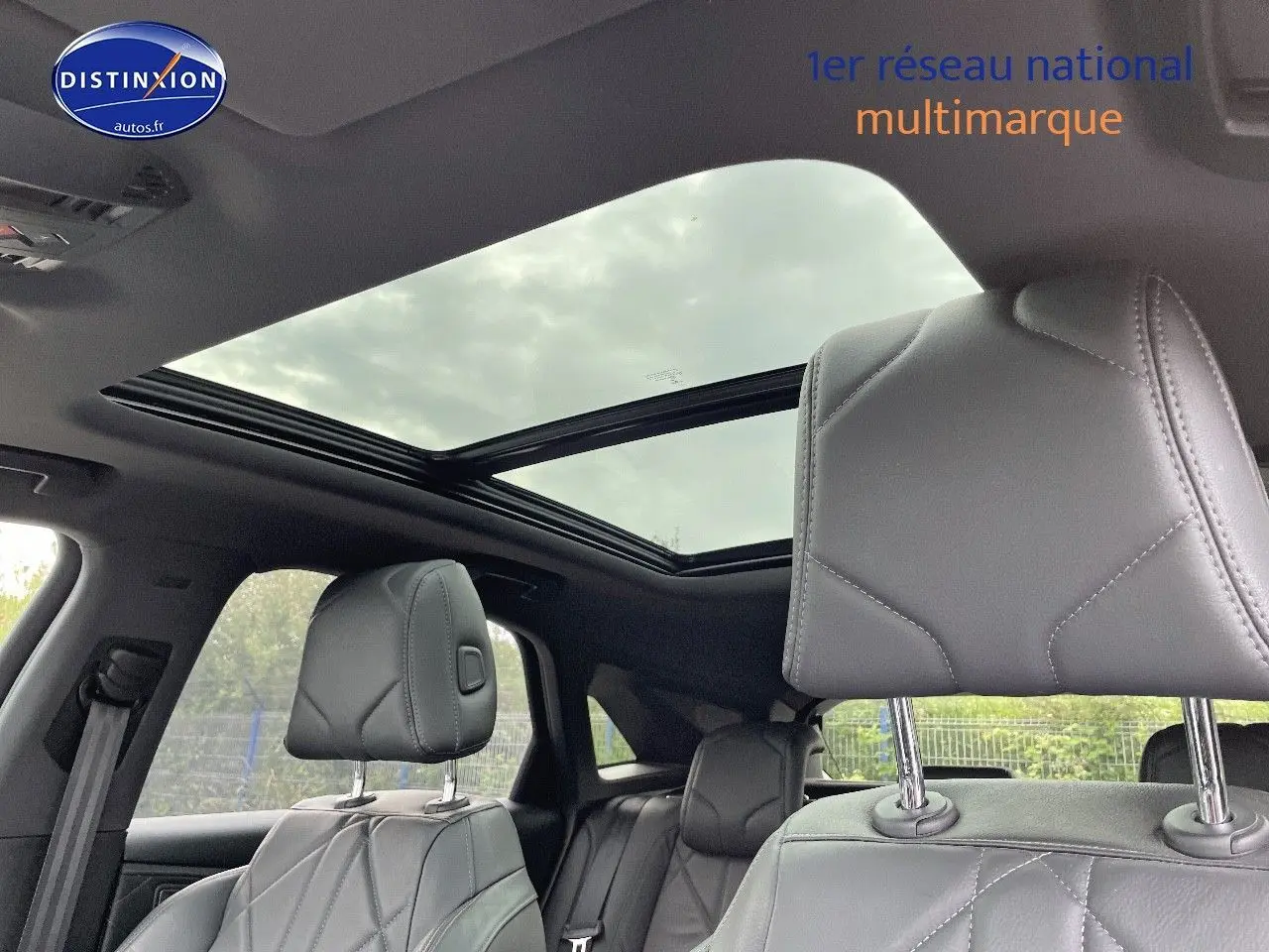 Intérieur du DS7 Crossback E-TENSE 2021 en cuir noir, vue sur les sièges avant et toit panoramique ouvert.