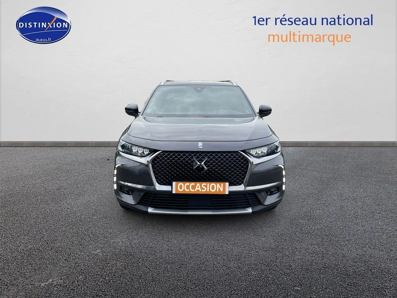 Vue frontale d'un DS7 Crossback gris platinium métal avec calandre distinctive et feux LED allumés.