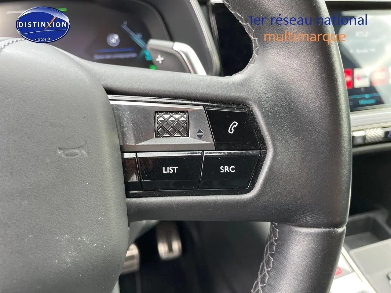 Gros plan sur les commandes au volant en cuir noir du DS7 Crossback E-TENSE 2021, avec tableau de bord digital en arrière-plan.