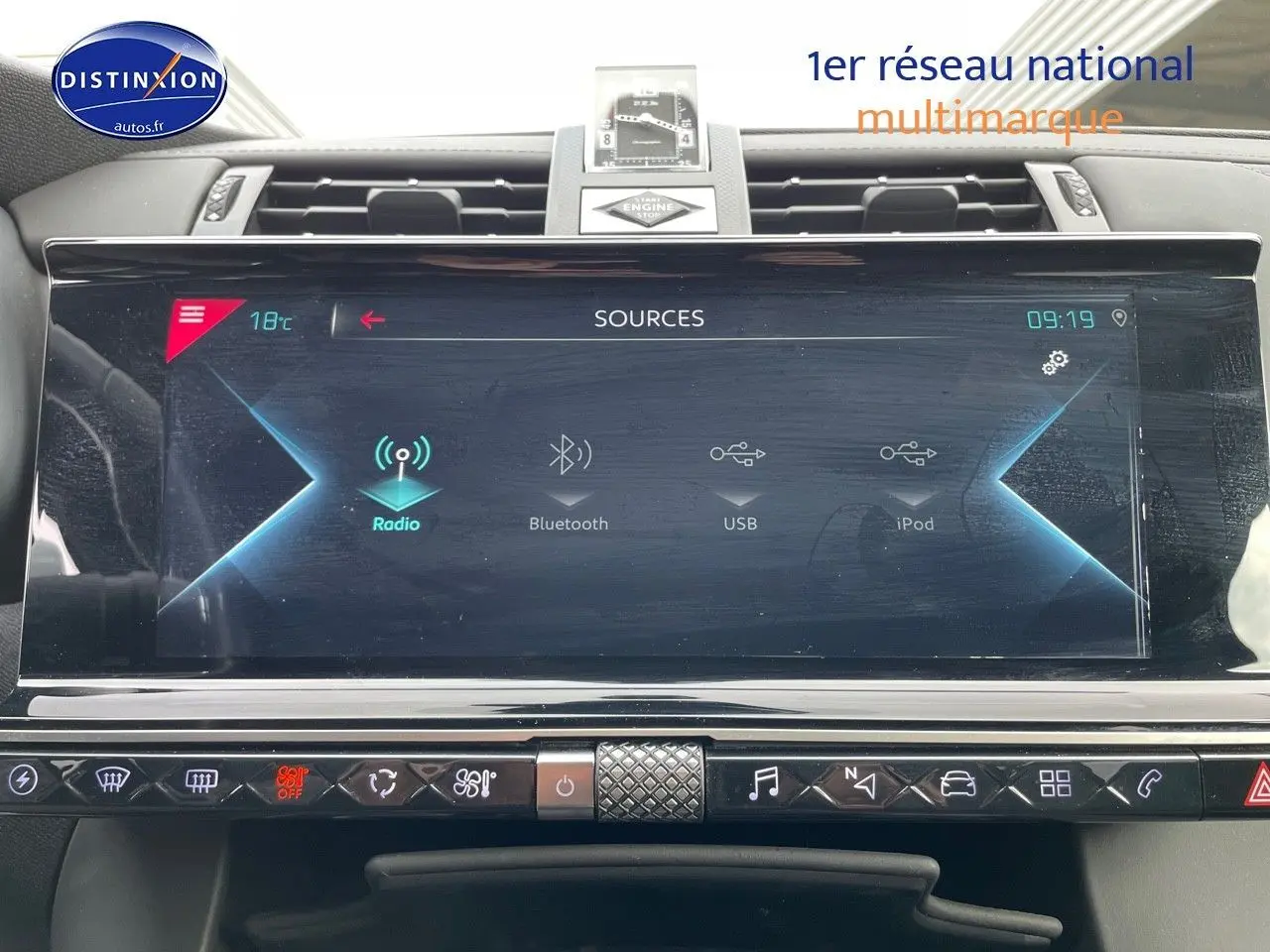 Écran tactile central du DS7 Crossback gris platinium, affichant les sources audio avec horloge et commandes tactiles.